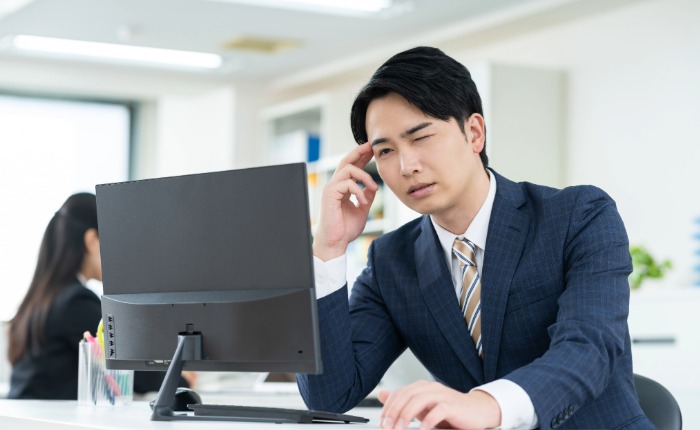 PCモニターを見ながら悩んでいるビジネスパーソン